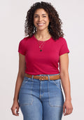 A woman with curly hair smiles, wearing the Woolx Addie Crew Neck in Poppy Spark against a plain background.
