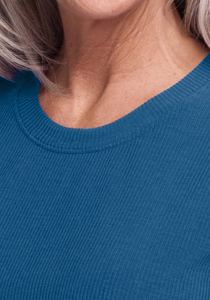 Close-up of an older woman wearing the Woolx Delia Ribbed Short Sleeve in Moroccan Blue, gray hair visible.
