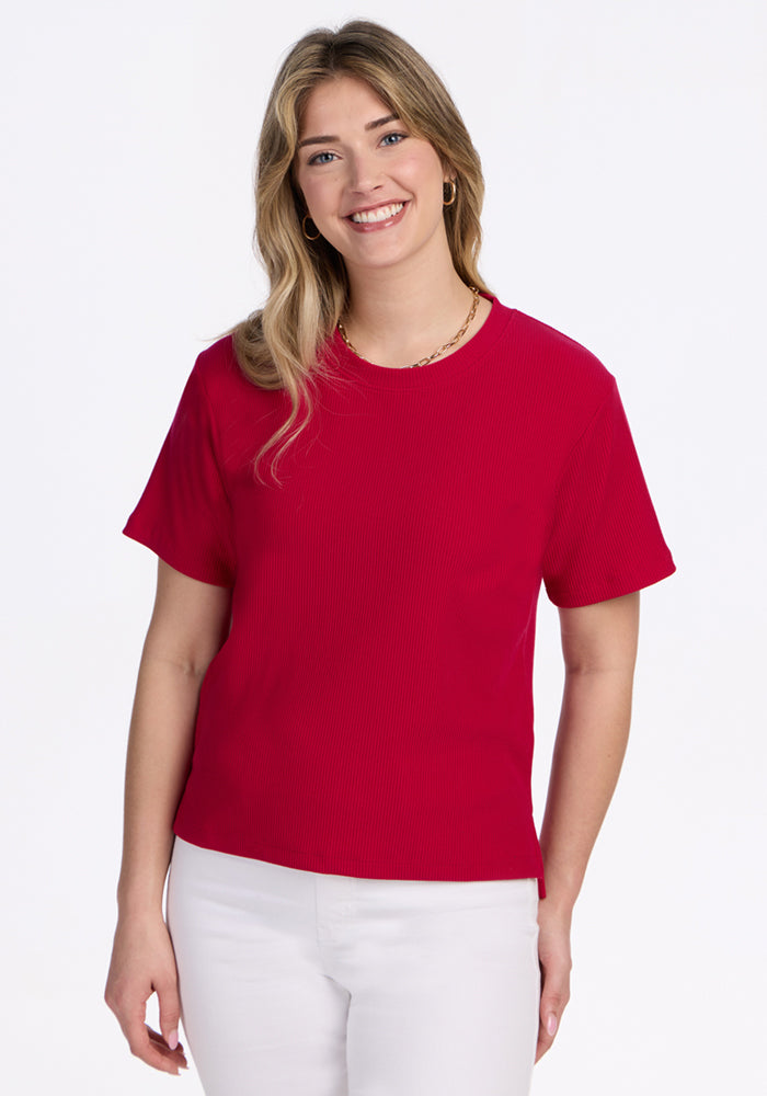 Smiling woman in a Woolx Delia Ribbed Short Sleeve in Poppy Spark and white pants, against a white background.