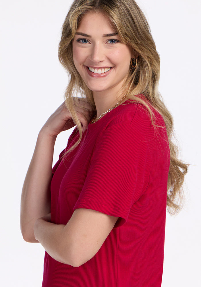Woman with long blonde hair smiles in the Woolx Delia Ribbed Short Sleeve in Poppy Spark against a white background.