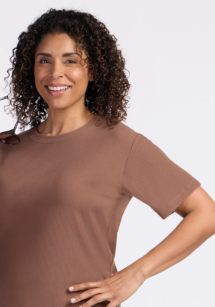 Smiling woman wears the Woolx Delia Ribbed Short Sleeve in Sienna Kiss, standing confidently with one hand on her hip.