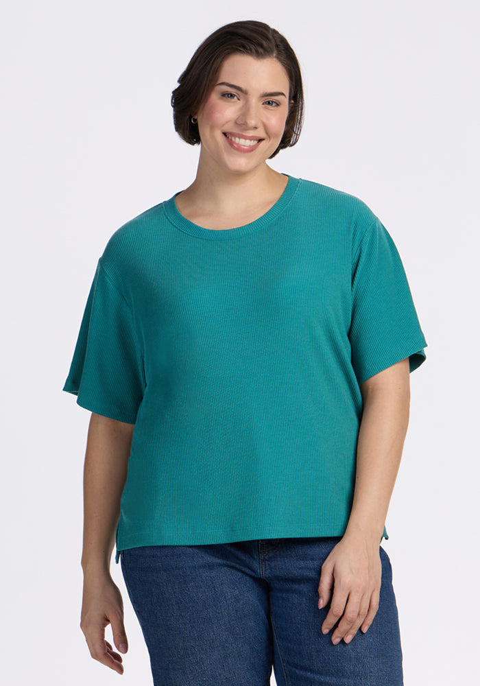 A woman in a Woolx Delia Ribbed Short Sleeve - Surfside shirt smiles at the camera against a white background.