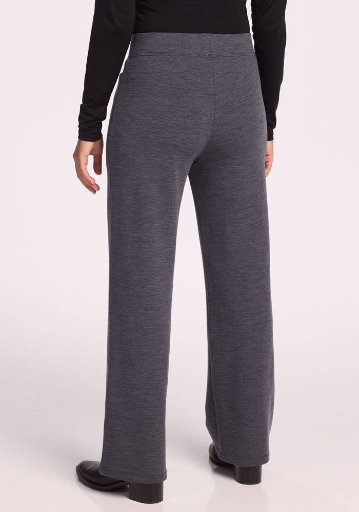 A person wearing Woolx Ellie Wide Leg Pants Petite in Cinder Melange, a black long-sleeve top, and black shoes stands with their back to the camera against a plain light background.