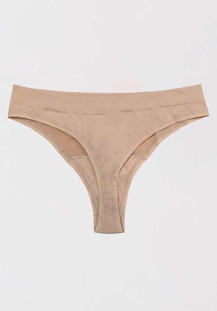The Woolx Farrah Thong in Sand is laid flat on a white background, showcasing its seamless thong design for discreet comfort and a smooth finish.