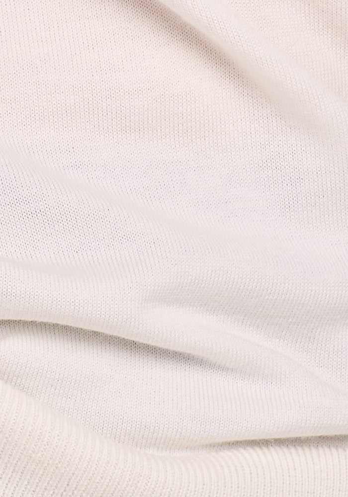 The Francesca Sweater - Dewdrop Pearl by Woolx features a soft, light beige ribbed fabric with subtle folds. Cozy and warm, it's crafted for breathability, making it an ideal travel-friendly Merino wool knit or woven piece.
