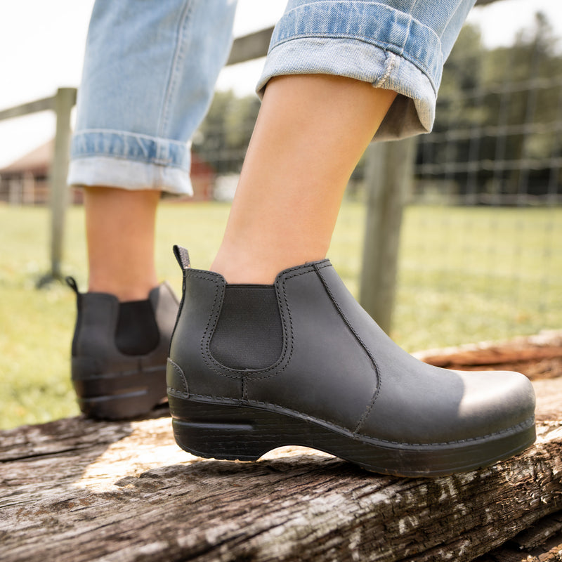 Black boots standing on a wooden plank.