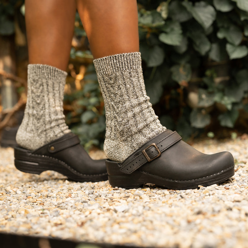 Black mule clogs with a swivel strap styled as backless with grey wool socks.