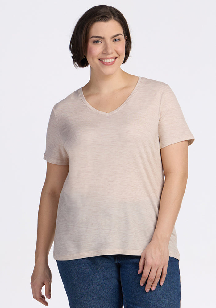A woman with short dark hair smiles while wearing the Woolx Junie V Neck in Cream Heather and blue jeans, standing against a plain white background. | Juliana is 5'10", wearing a size XL