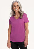 Smiling older woman in Woolx Junie V Neck in Purple Wine and black pants, with long gray hair.