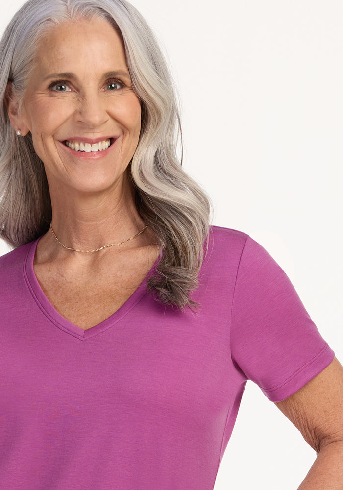 Smiling older woman in Woolx Junie V Neck tee, Purple Wine color, relaxed fit, against a light background.
