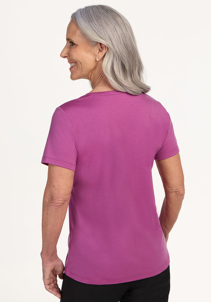 Smiling older woman in a relaxed fit, Woolx Junie V Neck tee in Purple Wine, shown from the back.