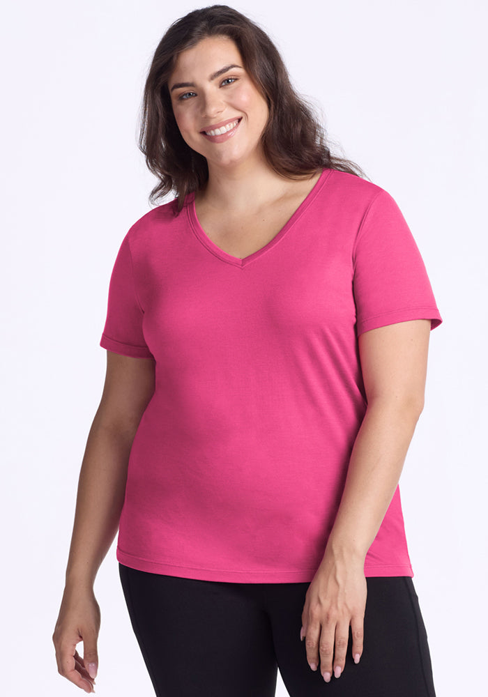 Woman smiles in a Woolx Junie V Neck (Raspberry Fizz), paired with black pants, against a plain background.