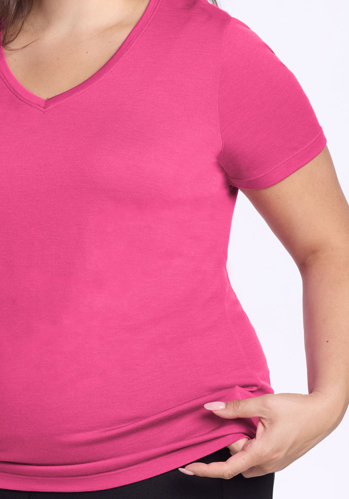 Someone in the Woolx Junie V Neck in Raspberry Fizz touches the hem, revealing part of their arm and waist.