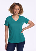 Woman with curly hair wears the Woolx Junie V Neck tee in Surfside and jeans, standing with one hand on her hip.