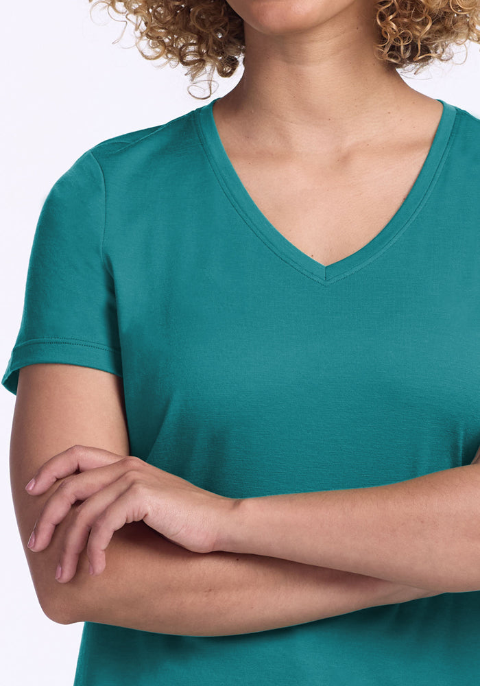 Curly-haired person in Woolx Junie V Neck tee in Surfside, relaxed fit, arms crossed, shown shoulders down.