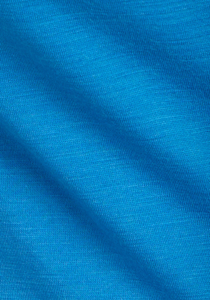 Close-up of the Woolx Junie V Neck in Wave Rider shows blue moisture-wicking fabric with textured diagonal folds.