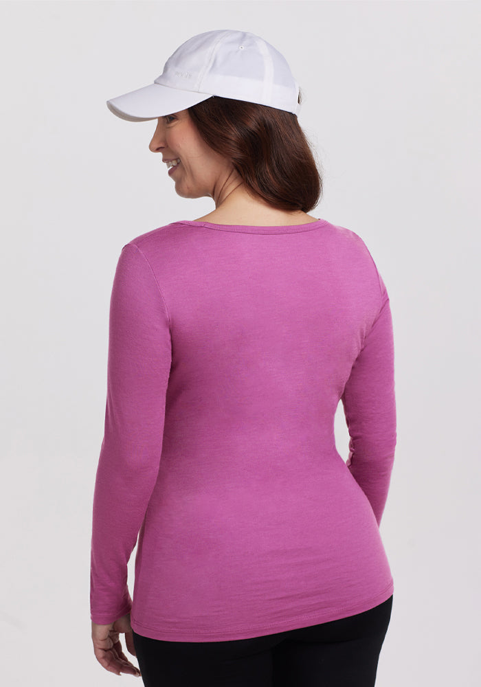 Woman in Woolx Layla V Neck Top in Purple Wine and white cap, facing away against a plain background.
