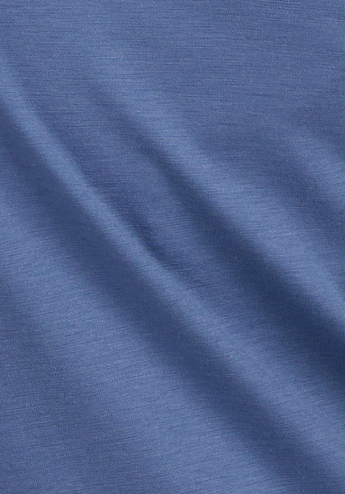 The Woolx Layla V Neck Top in Skyline features soft blue fabric with gentle folds and a smooth, slightly textured finish.
