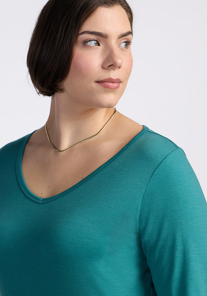 Woman with short brown hair in a Woolx Layla V Neck Top in Surfside, wearing a gold necklace, looking left.