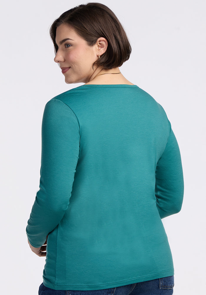 A woman in the Woolx Layla V Neck Top in Surfside, shown from the back, looks over her shoulder. Final Sale.