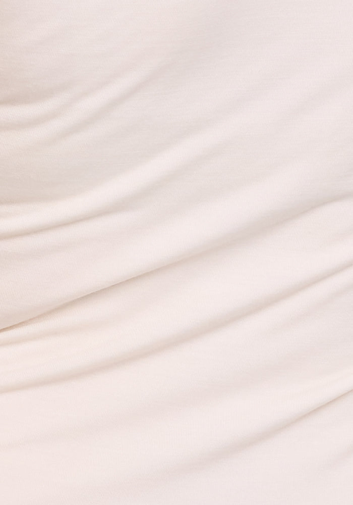 Close-up of the Woolx Maggie Bodysuit in Vanilla, made from soft Merino wool with smooth, flowing folds and subtle texture. This fabric is both temperature-regulating and moisture-wicking for comfort.