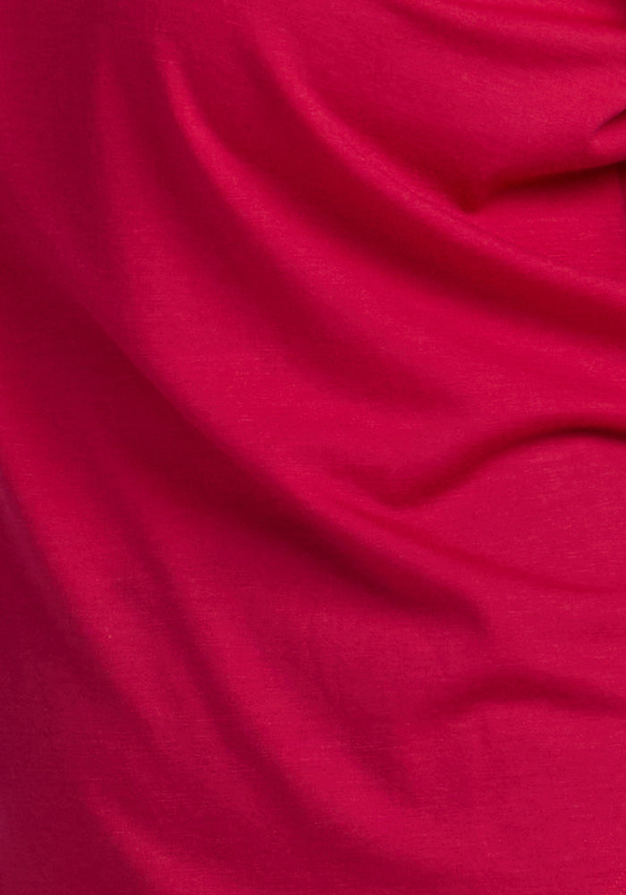 Close-up of the Woolx Millie Long Sleeve in Poppy Spark: bright pink, soft, moisture-wicking fabric with visible folds.
