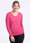 Smiling woman in Woolx Millie Long Sleeve - Raspberry Fizz & black pants, standing against a light background.