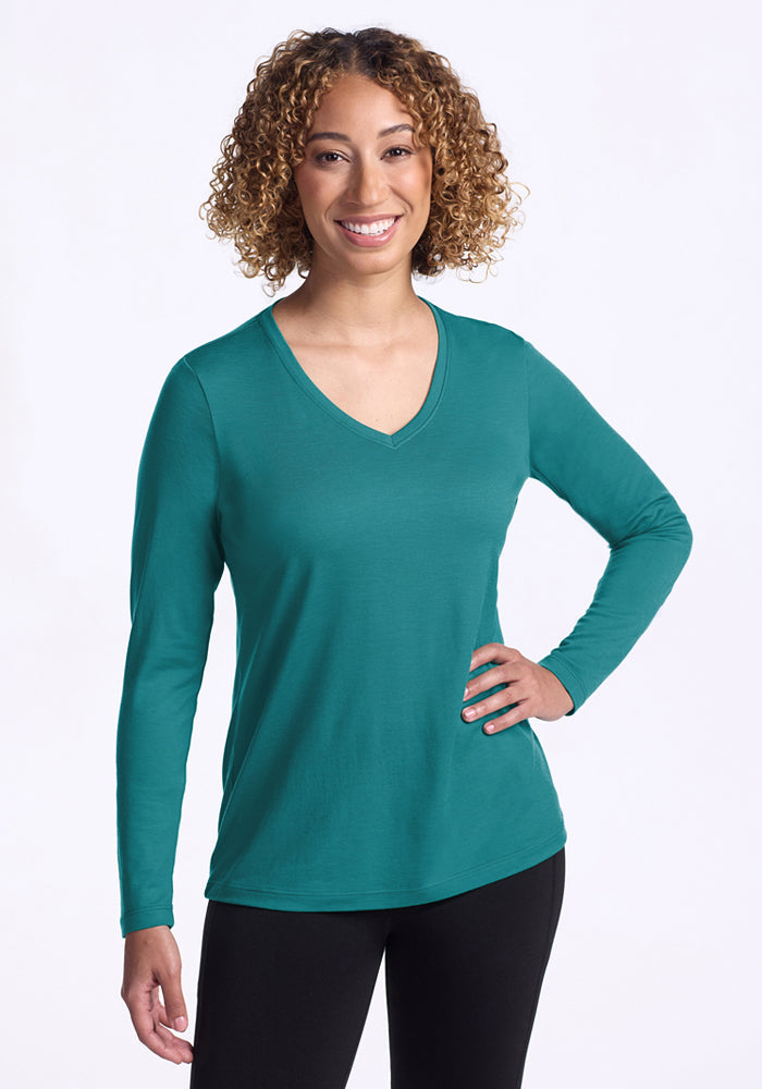 Woman smiling in Woolx Millie Long Sleeve • Final Sale - Surfside top and black pants, hand on hip.