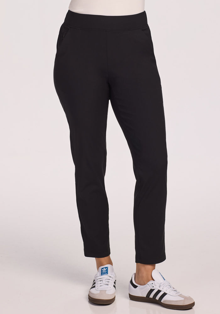 A person wears Woolx Nicole Pants in black and white Adidas sneakers with black stripes, standing against a plain white background. Their upper body is mostly out of frame.