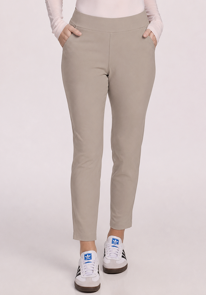 Model in Nicole Petite Ankle Pant - Vintage Khaki by Woolx and white Adidas sneakers, hands in pockets, waist to feet.