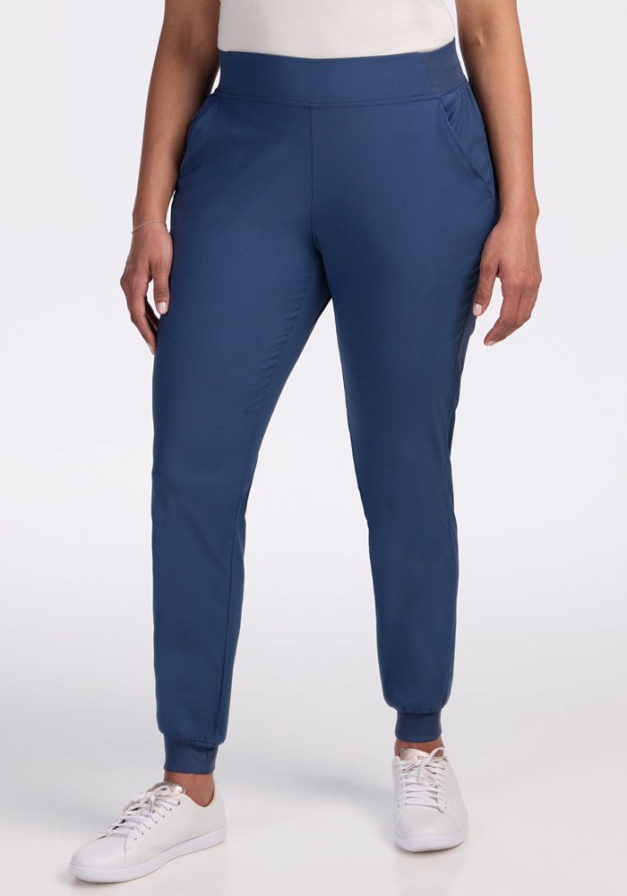 Wearing Woolx Palmer Joggers in Vintage Indigo with side pockets and a relaxed fit, paired with a white top and white sneakers, a person stands against a plain white background. | Kisha is 5’8”, wearing a size M