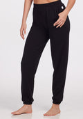 A person is wearing Woolx Parker Sweatpants - Black, featuring a relaxed fit, elastic waistband and cuffs, and moisture-wicking Merino wool, while standing barefoot against a plain white background. | Karly is 5'10", wearing a size S