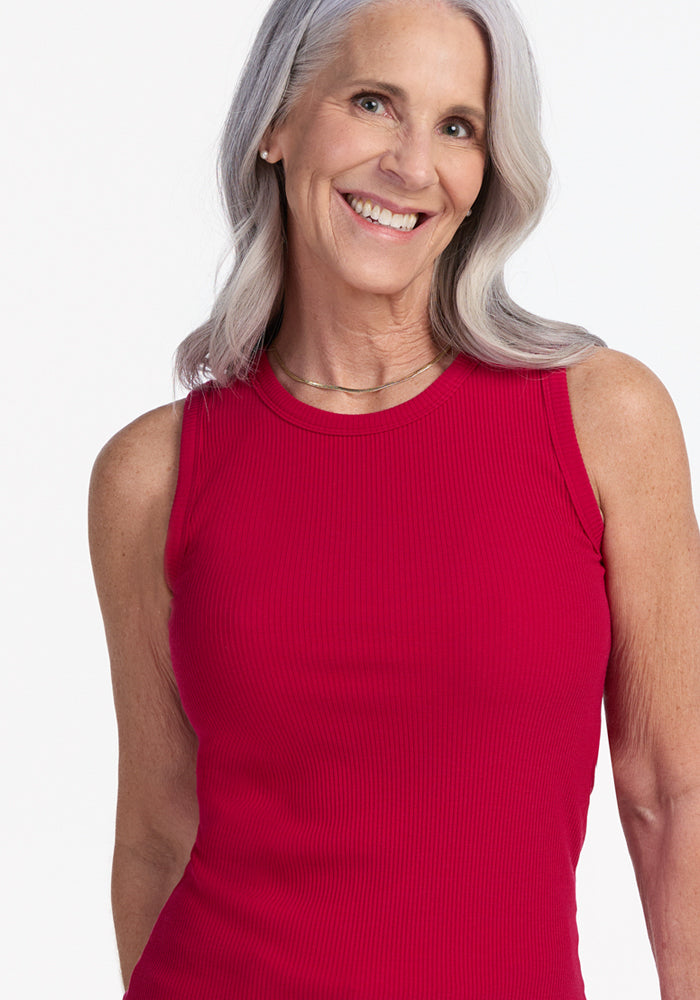 Smiling older woman wears the Woolx Raegan Ribbed Tank Top in Poppy Spark, standing against a white background.