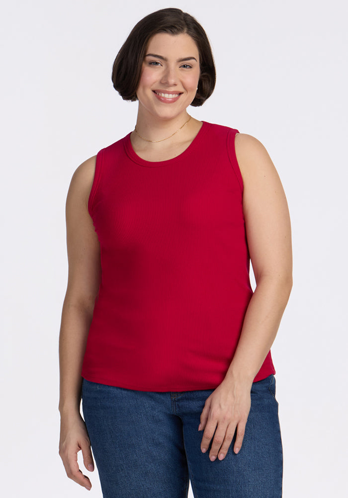 Smiling woman wears the Woolx Raegan Ribbed Tank Top in Poppy Spark with blue jeans against a white background.
