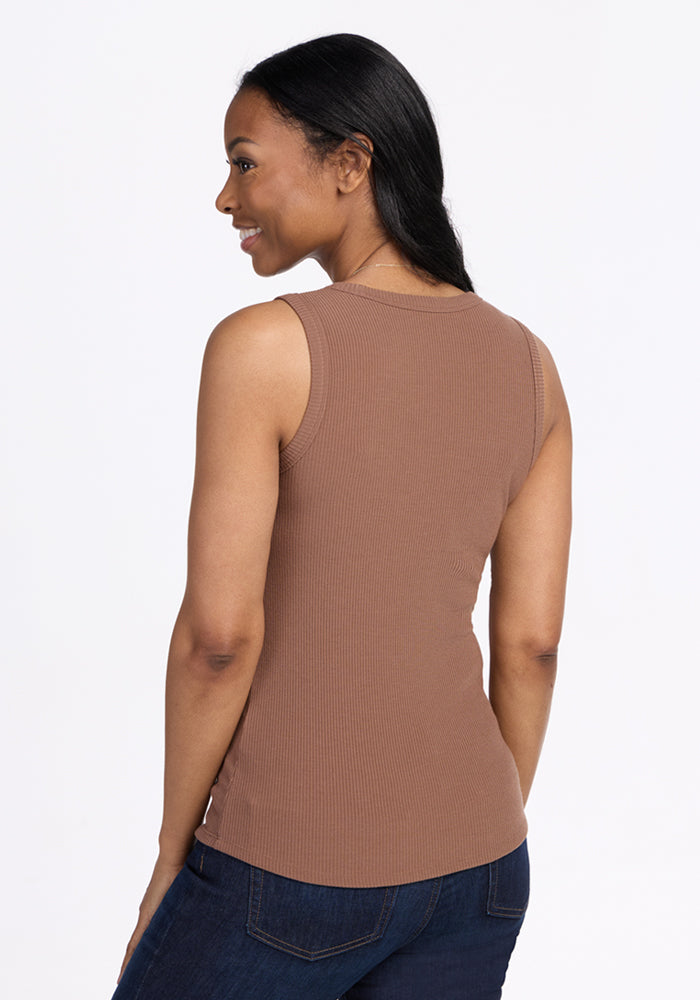 Smiling over her shoulder, a woman wears the Woolx Raegan Ribbed Tank Top in Sienna Kiss and dark jeans.