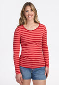 A woman with long light brown hair smiles against a white background, wearing the Woolx Remi Long Sleeve T-Shirt in Wildberry Stripe paired with denim shorts. | Ariana is 5'11", wearing a size S