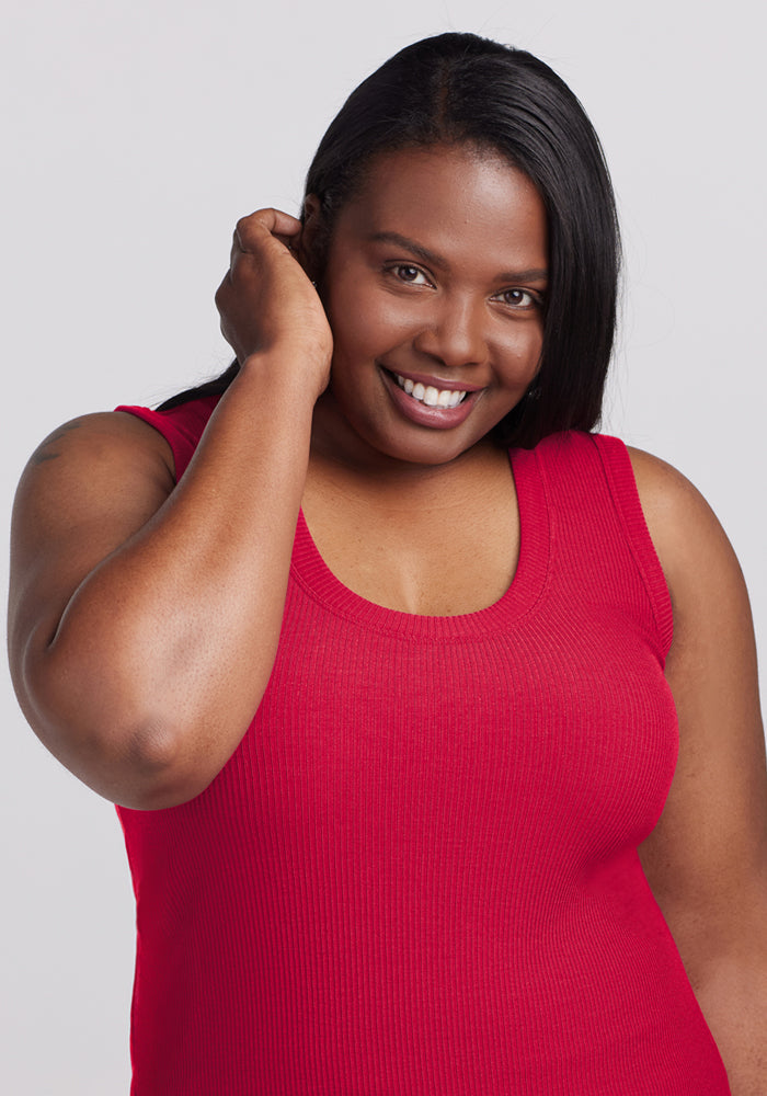 Smiling woman wears the Woolx Sloane Ribbed Tank in Poppy Spark, posing against a plain light background.