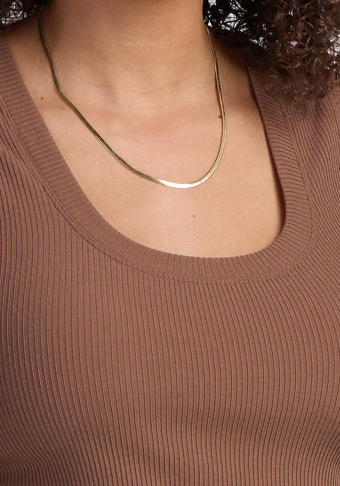 Someone wears the Woolx Sloane Ribbed Tank in Sienna Kiss with a simple gold chain necklace.