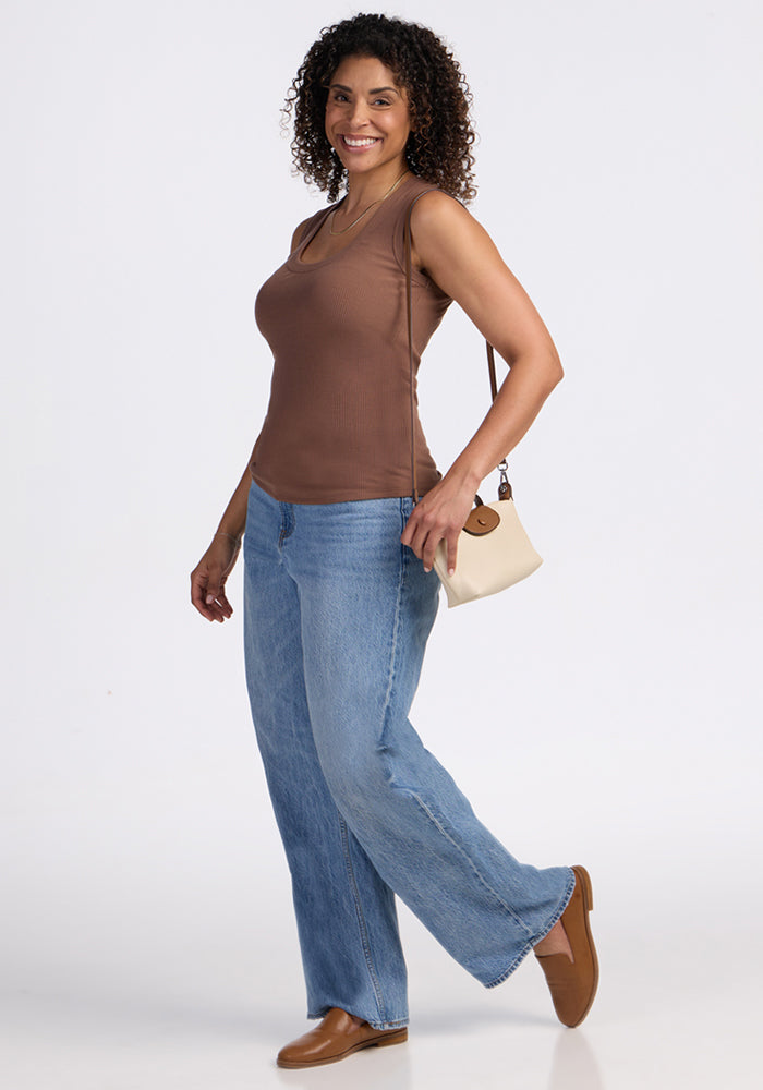 Smiling woman wears the Woolx Sloane Ribbed Tank in Sienna Kiss, blue jeans, brown shoes, and a beige purse.
