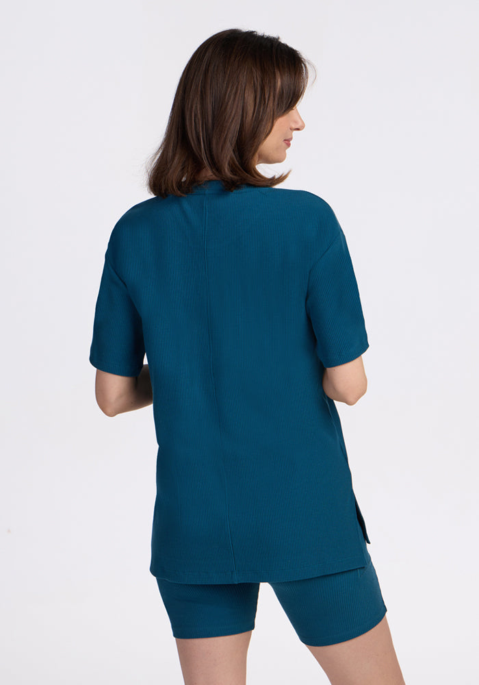 Woman with shoulder-length brown hair wears the Woolx Vera Ribbed Tunic in Moroccan Blue, back turned.