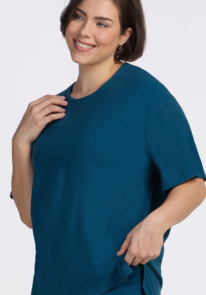 A woman with short brown hair smiles in the Woolx Vera Ribbed Tunic in Moroccan Blue against a light background.
