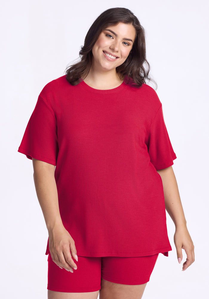 Smiling woman in the Woolx Vera Ribbed Tunic in Poppy Spark stands against a plain white background.