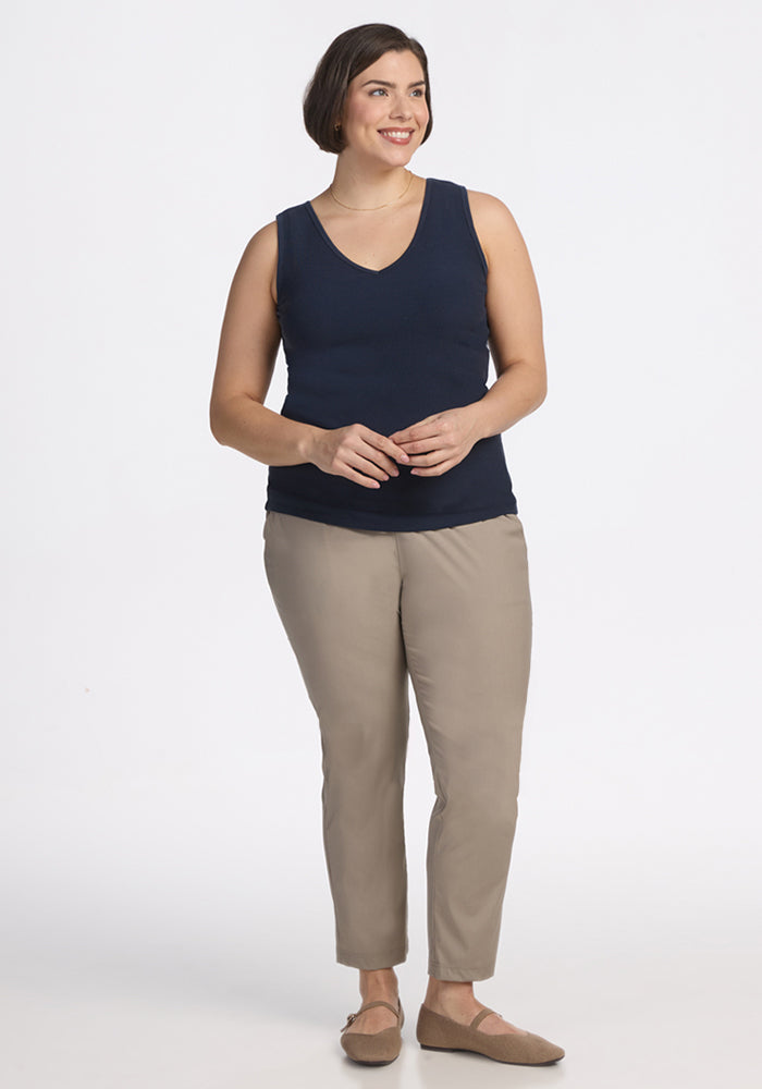 Woman smiling in a Woolx Vivi Ribbed Tank in Deep Navy, beige pants, and tan shoes against a white background.