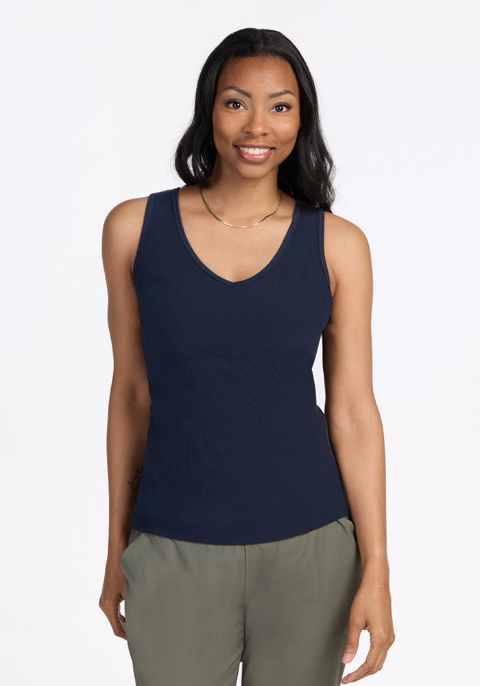 Woman wearing the Woolx Vivi Ribbed Tank in Deep Navy, smiling and standing against a plain light background.