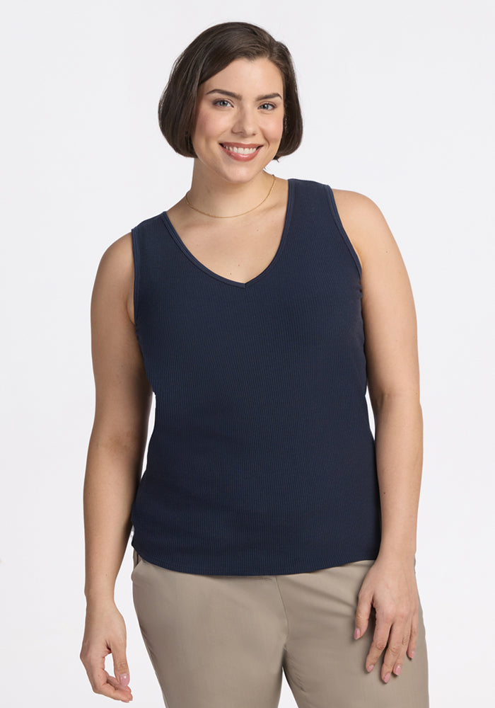 Smiling woman with short brown hair wears Woolx Vivi Ribbed Tank in Deep Navy and beige pants against a white background.