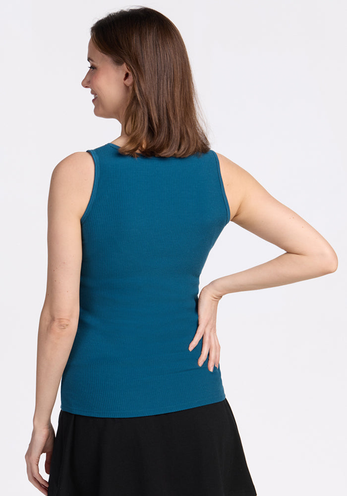 Woman in a Woolx Vivi Ribbed Tank in Moroccan Blue stands with her back to the camera, hand on hip.