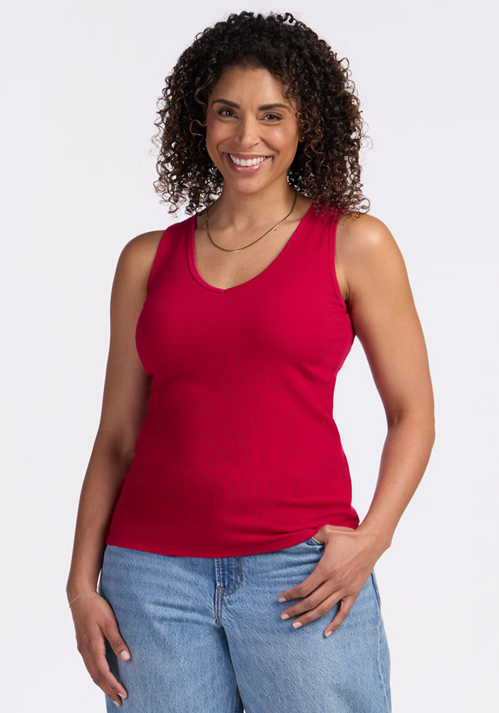 Smiling woman in Woolx Vivi Ribbed Tank in Poppy Spark, standing against a white background.
