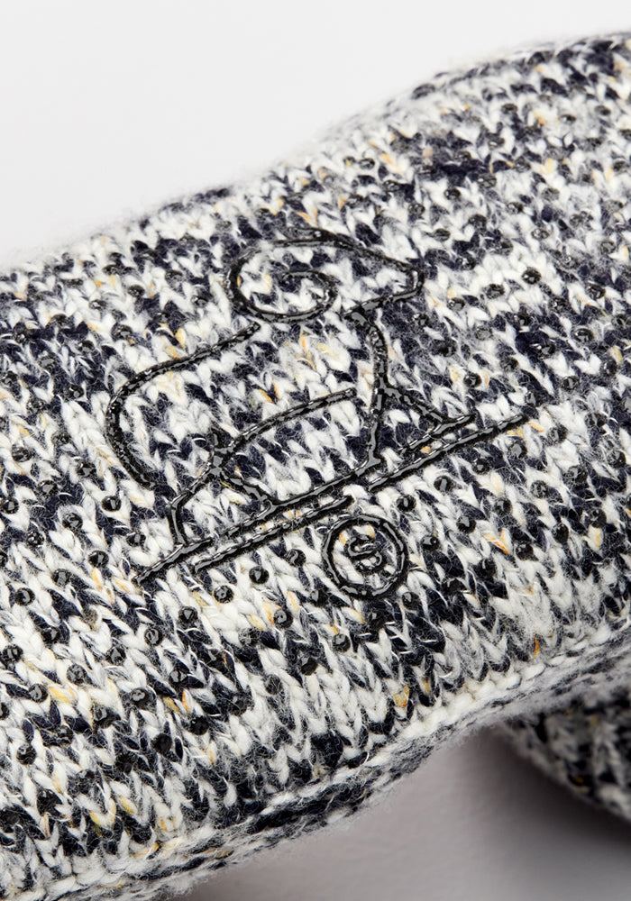 Close-up of Women's Gripper Slipper Booties - Speckled Stone by Woolx, featuring speckled black, white, and gray woolen knit with an embroidered dog on a skateboard—ideal for cozy comfort.