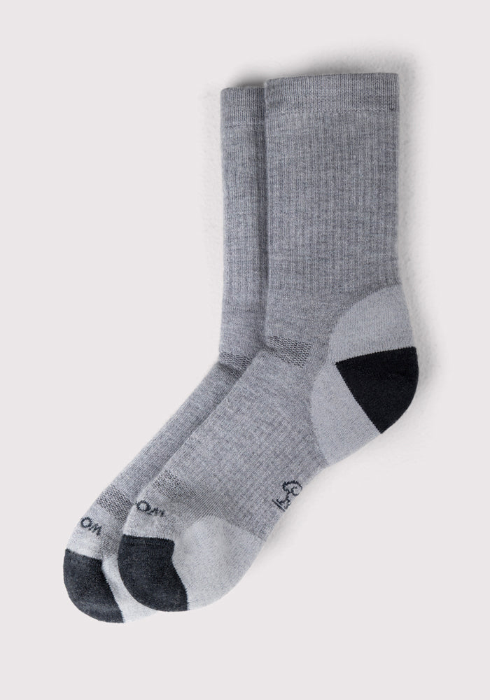 A pair of Woolx Womens Core Crew Socks in light gray, with darker gray heels and toes, shown flat. These odor-resistant socks have ribbed cuffs and reinforced heels and toes for comfort and durability.