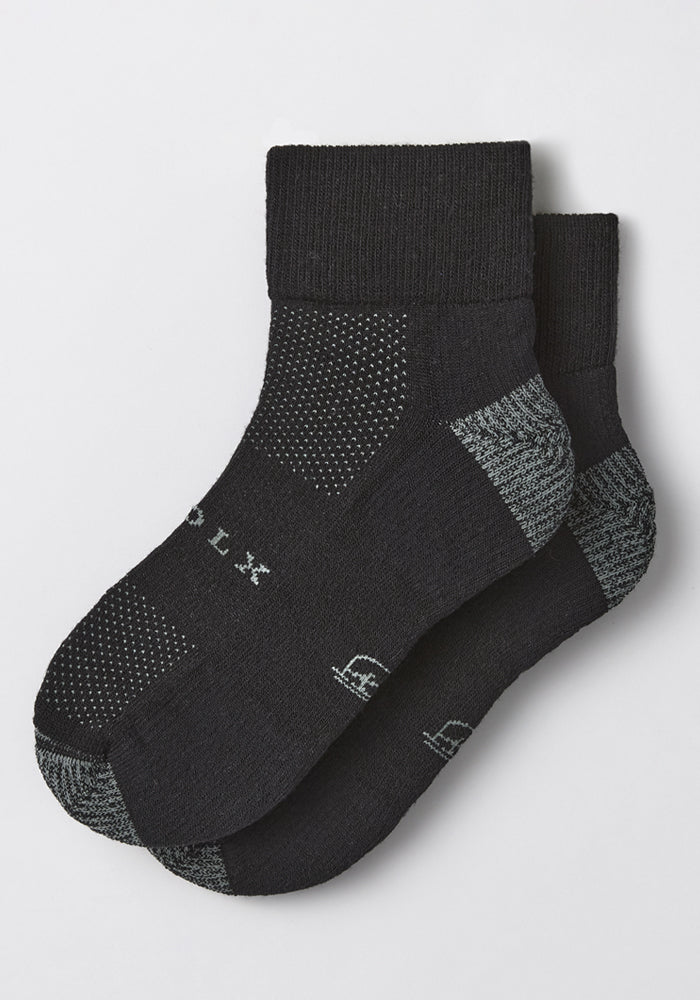 The Woolx Womens Rambler Ankle Sock - Black Pepper features black ankle socks with gray accents, a textured knit pattern, white side text, and superior moisture management for lasting comfort.